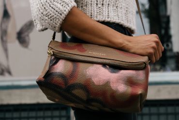 Close-up of a person holding a stylish Burberry leather handbag.